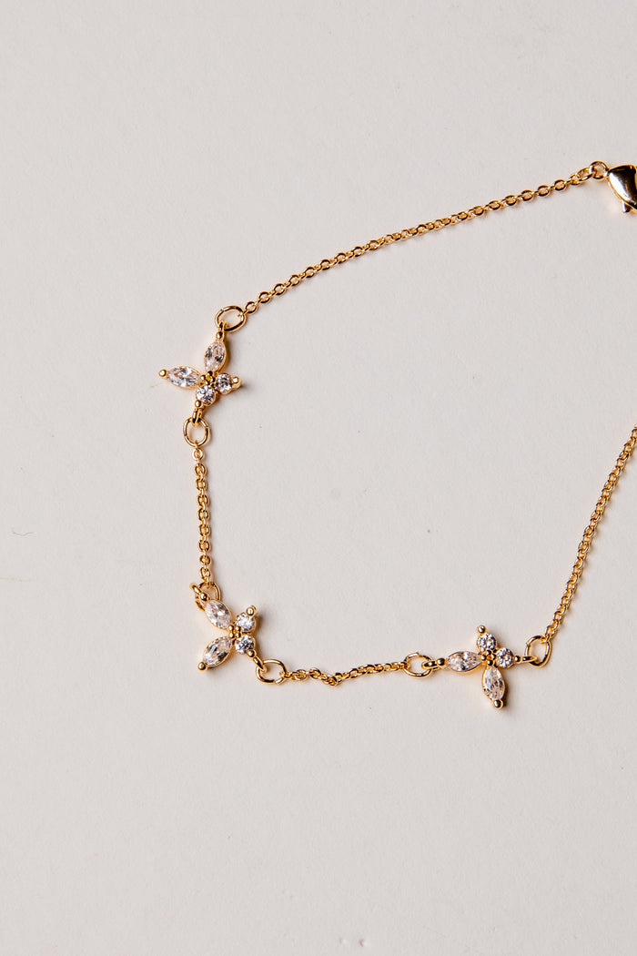 Gold bracelet with cross charms on a light gray background