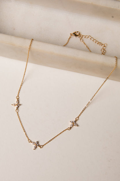 Gold necklace with star-shaped pendants on a light wooden surface