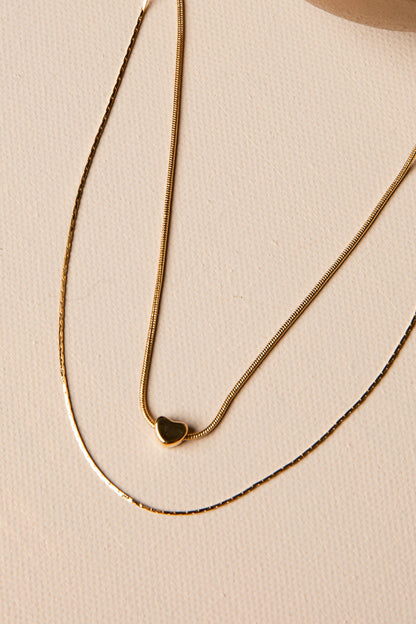 Gold necklace with a heart pendant on a beige background