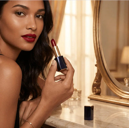 Woman applying deep red matte lipstick, elegant vanity background, beauty product focus