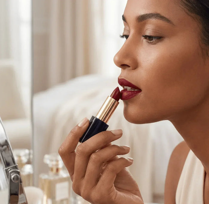 Woman applying matte red lipstick indoors, close-up beauty and makeup application