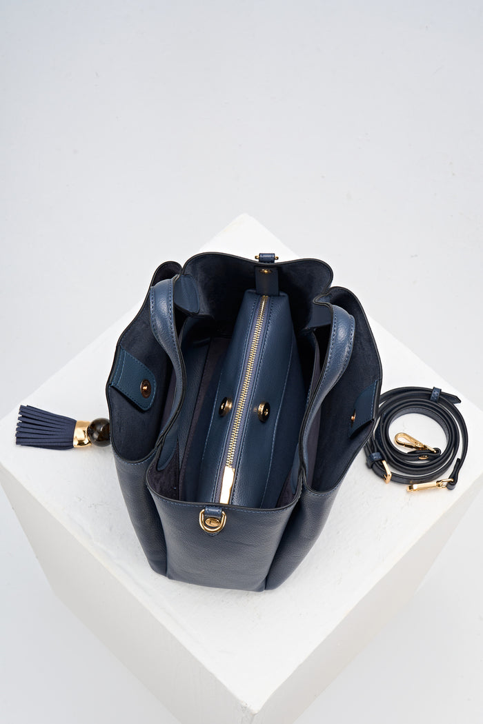 Overhead view of Etta Denim Blue faux leather Small Tote showing the inside and removable interior pouch with detachable crossbody strap rolled up next to the bag