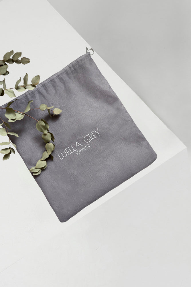 Luella Grey dust bag in grey with Luella Grey logo in white displayed on a white plinth