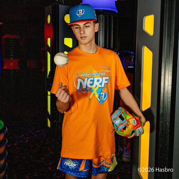 Person wearing a bright orange NERF t-shirt holding a colorful glove and ball in front of colorful background
