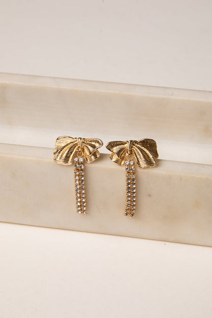 Gold earrings with tassel design on a beige surface