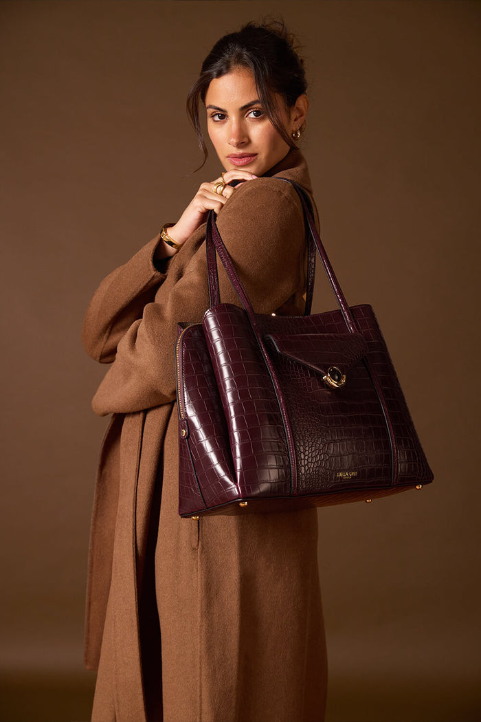 Female model holding Francois Black Cherry Crocodile print faux leather Laptop Tote over her shoulder showing the front and side of the bag