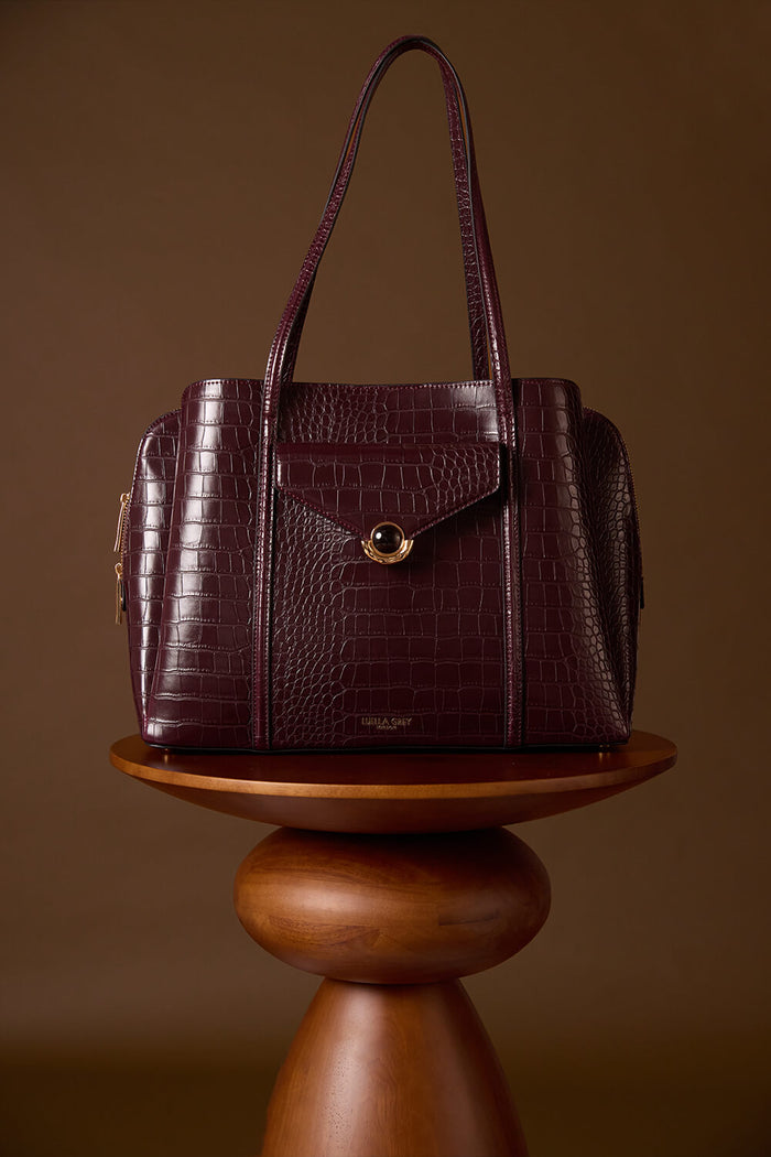 Francois Black Cherry Crocodile print faux leather Laptop Tote displayed on a brown wooden plinth