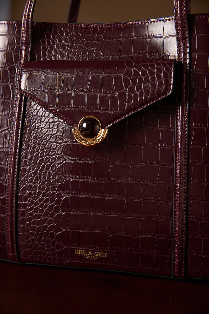 Close up of the front of Francois Black Cherry Crocodile print faux leather Laptop Tote focusing on the Molten Metal Crystal Palace Clasp closure on the front slip in pocket