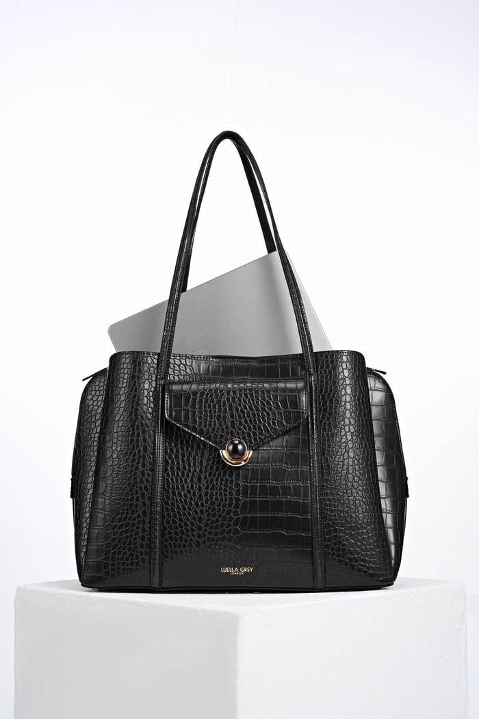 Front view of Francois Black Crocodile print faux leather Laptop Tote with laptop inside and resin and gold Crystal Palace clasp closure detail on front flap