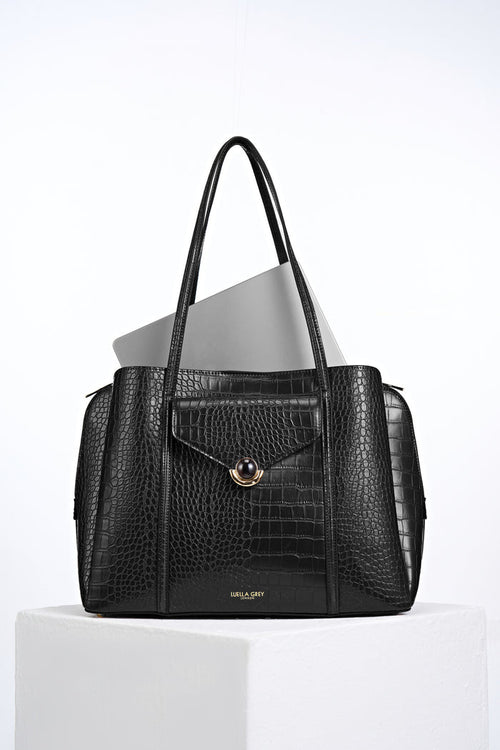 Front view of Francois Black Crocodile print faux leather Laptop Tote with laptop inside and resin and gold Crystal Palace clasp closure detail on front flap