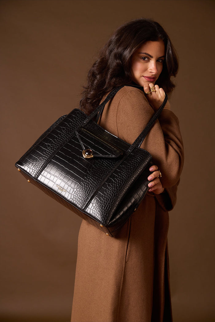 Female model holding Francois Black Crocodile print faux leather Laptop Tote over her shoulder showing the front of the bag