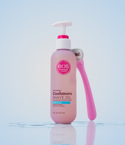 Pink bottle of eos Cashmere Shave Oil with a pump on a reflective surface.