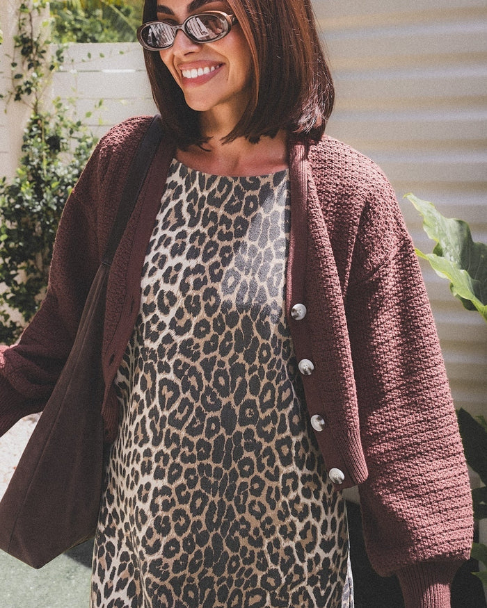 Woman wearing a leopard print dress and brown cardigan outdoors