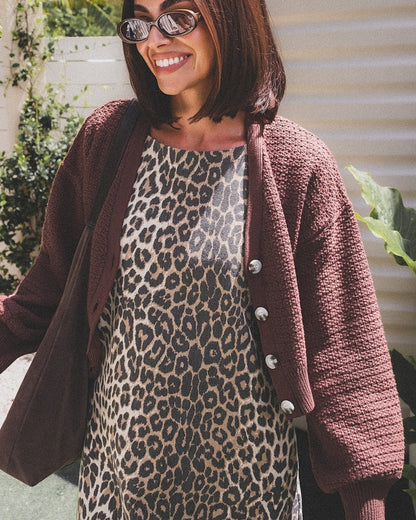 Woman wearing a leopard print dress and brown cardigan outdoors