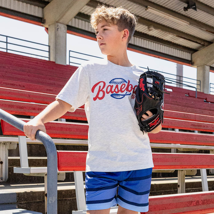 Boy holding a glove at red stadium bleachers looking sideways wearing a white heather Baseball Lifestyle graphic tee and royal blue striped mesh shorts