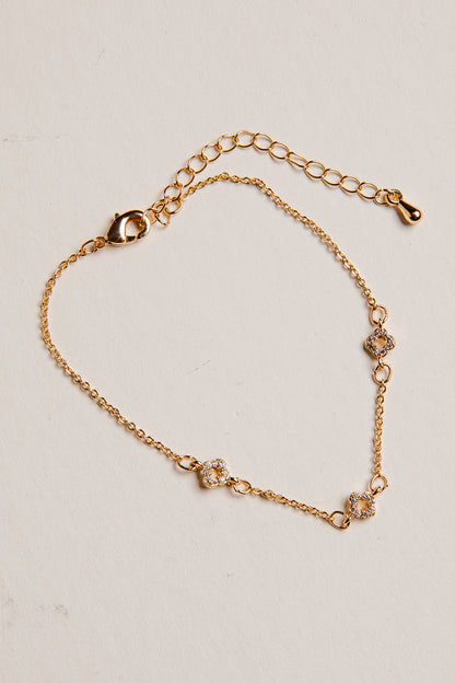 Gold bracelet with floral designs on a beige background