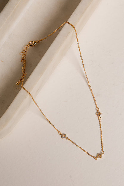 Gold necklace on a light beige surface