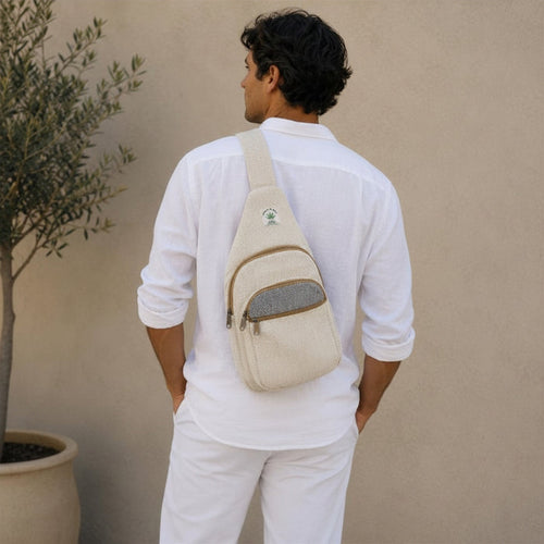 Man wearing a beige crossbody bag against a beige wall