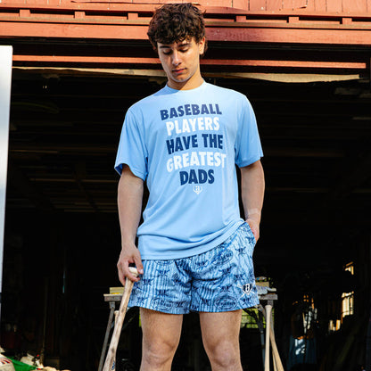 Young adult male model looking down while holding a wooden baseball bat and wearing the columbia blue Father & Son Bat Company Heritage Diamond Shorts paired with the columbia blue Greatest Dad Athletic Tee.
