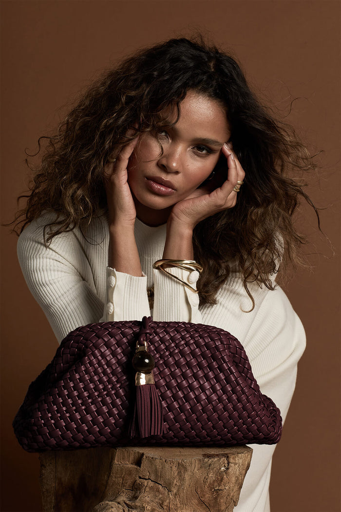 Female model posing behind Indigo Black Cherry woven faux leather Oversized Clutch