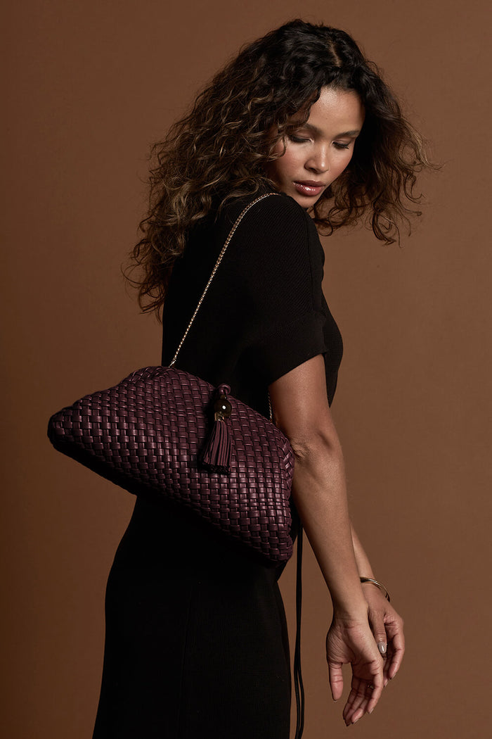 Female model wearing Indigo Black Cherry woven faux leather Oversized Clutch using the detachable gold metal chain over her shoulder