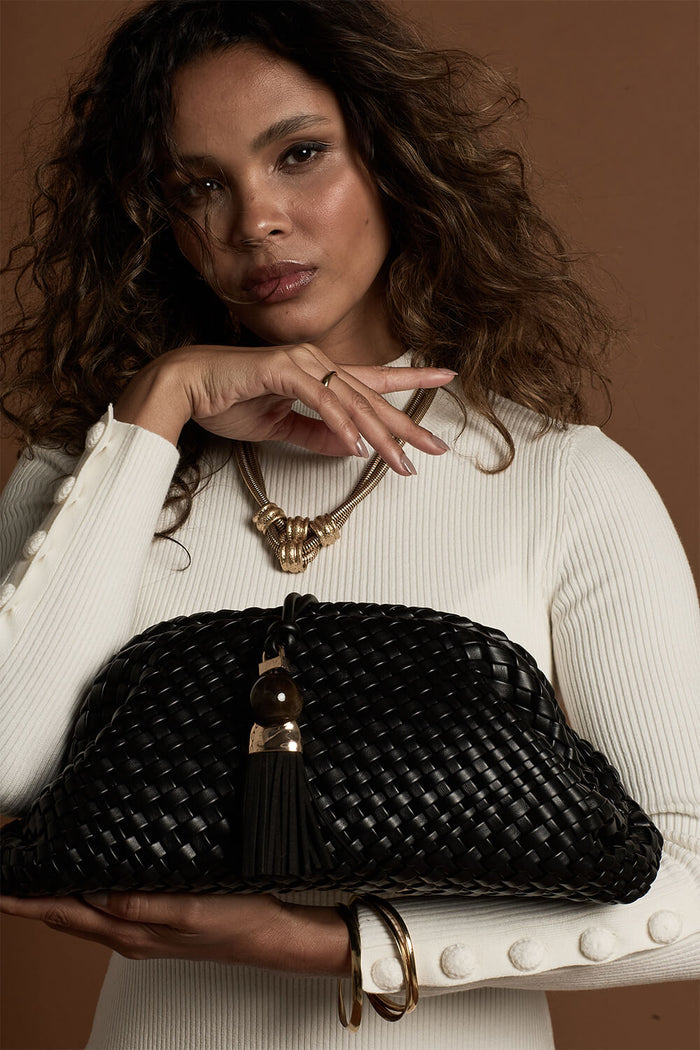 Female model holding Indigo Black woven faux leather Oversized Clutch by the bottom