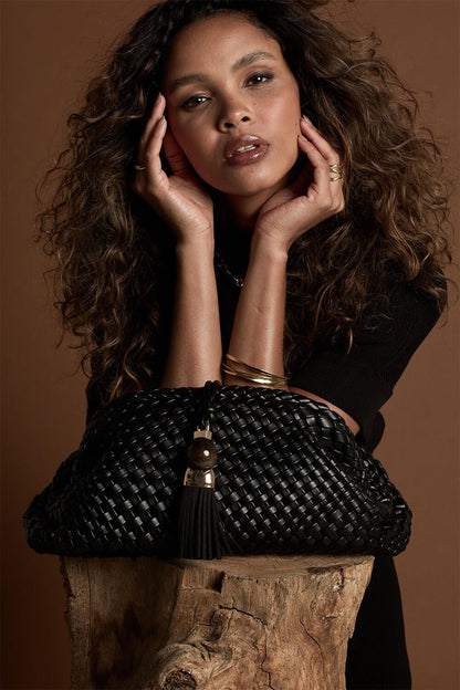 Female model posing behind Indigo Black woven faux leather Oversized Clutch