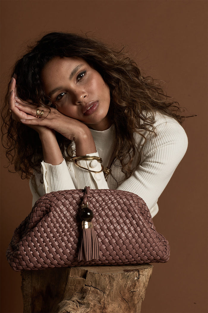 Female model posing behind Indigo Pecan woven faux leather Oversized Clutch