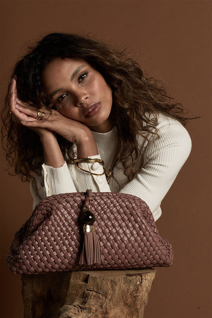 Female model posing behind Indigo Pecan woven faux leather Oversized Clutch