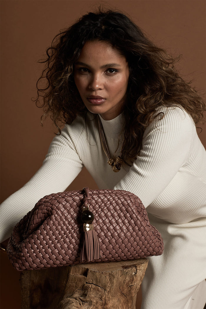 Female model posing behind Indigo Pecan woven faux leather Oversized Clutch
