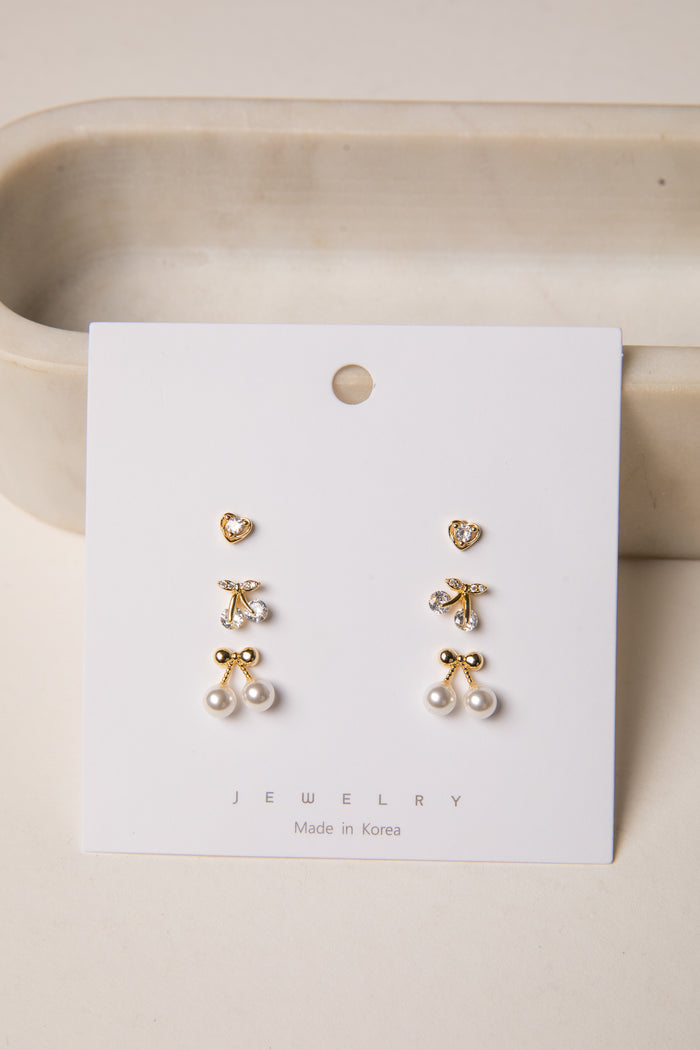Set of gold earrings on a white card with 'Jewelry' text, displayed on a beige surface.
