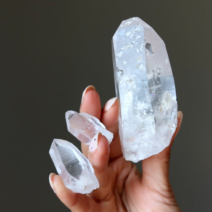Hand holding three crystal points against a dark background
