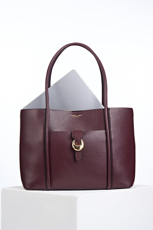 Front of Lilibet Black Cherry faux leather Laptop Tote with a laptop in the top showing molten metal Cannon Street Clasp closure on front slip-in pocket