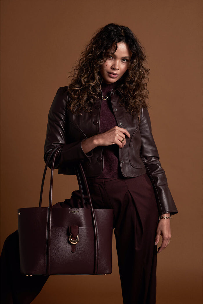 Female model holding Lilibet Black Cherry faux leather Laptop Tote over her arm by the shoulder straps