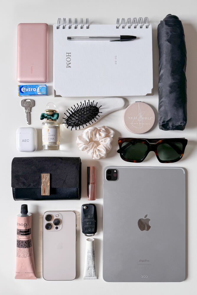 Collection of everyday items including a laptop, notepad, and various personal belongings showing what can fit in Lilibet faux leather Laptop Tote