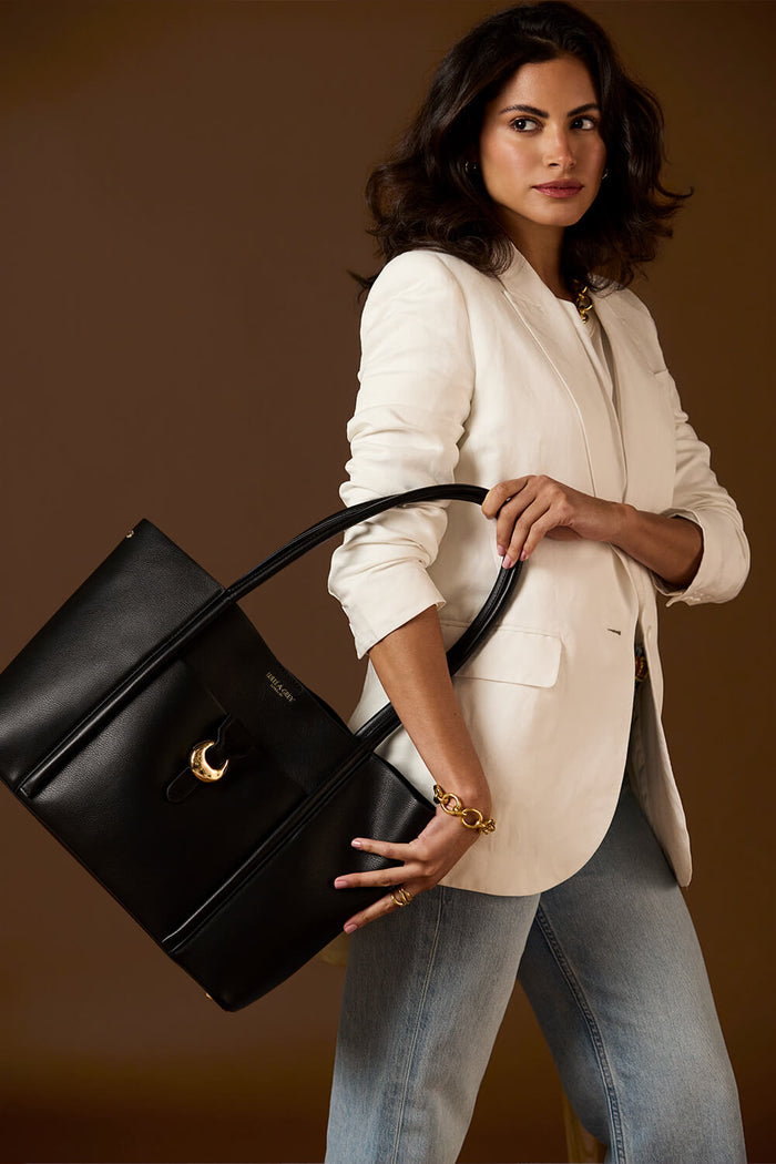 Female model holding Lilibet Black faux leather Laptop Tote in her hand by the shoulder straps
