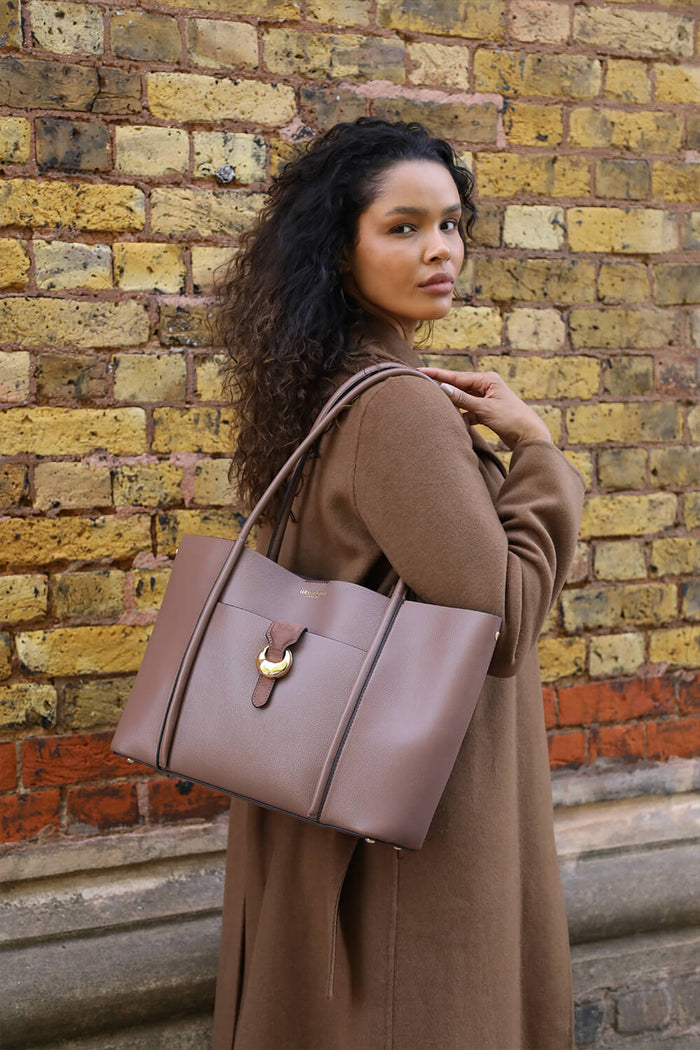 Female model holding Lilibet Fawn faux leather Laptop Tote over her shoulder using the two shoulder straps