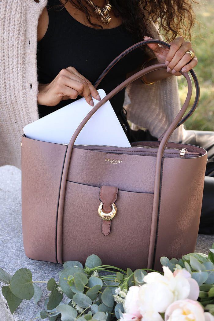 Female model putting a laptop into the detachable laptop pocket of Lilibet Fawn faux leather Laptop Tote