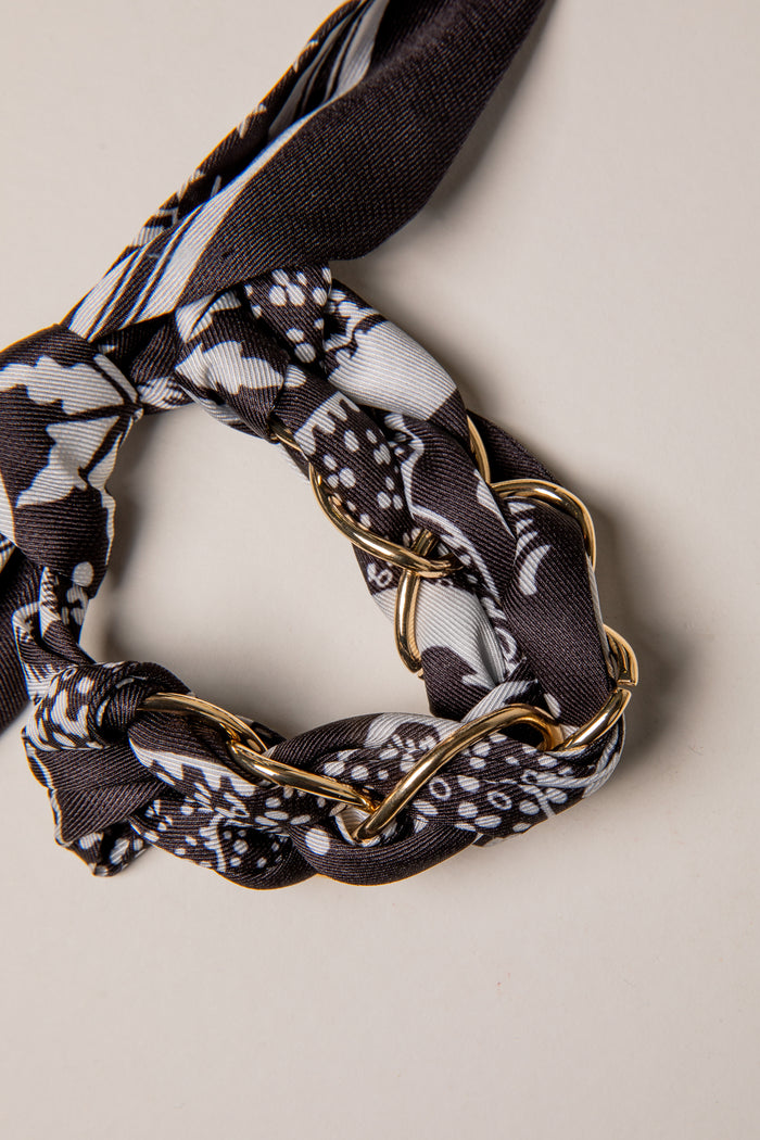 Scarf with gold chain detail on a neutral background