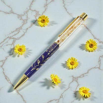 Decorative pen with gold accents on a marble surface with yellow flowers