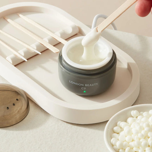 stirring a mini wax heater with waxing pellets from the london beauty company