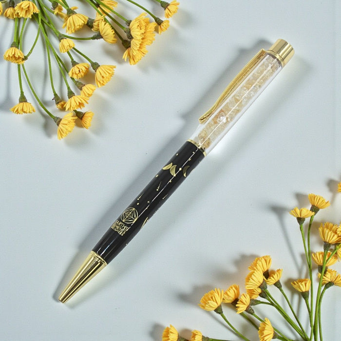Decorative pen with gold accents on a light blue background with yellow flowers.