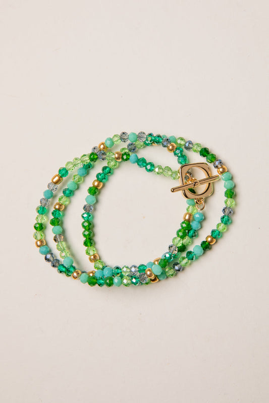 Multistrand beaded bracelet with a gold clasp on a beige background