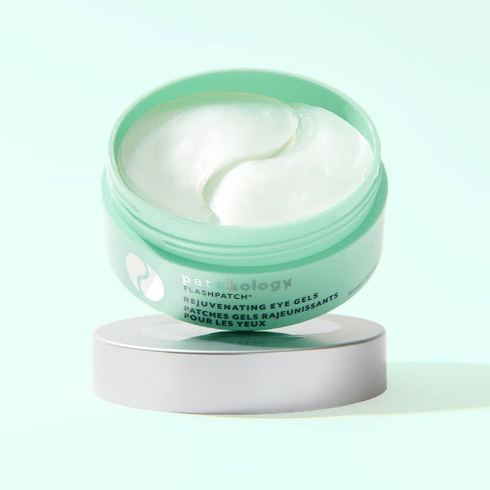 Open mint green jar of rejuvenating eye gels showing pearly white patches inside, tilted on its silver lid against a pale mint background