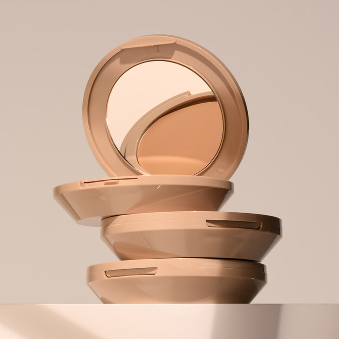 A stack of three FlexShade Foundation by No Makeup Makeup compacts