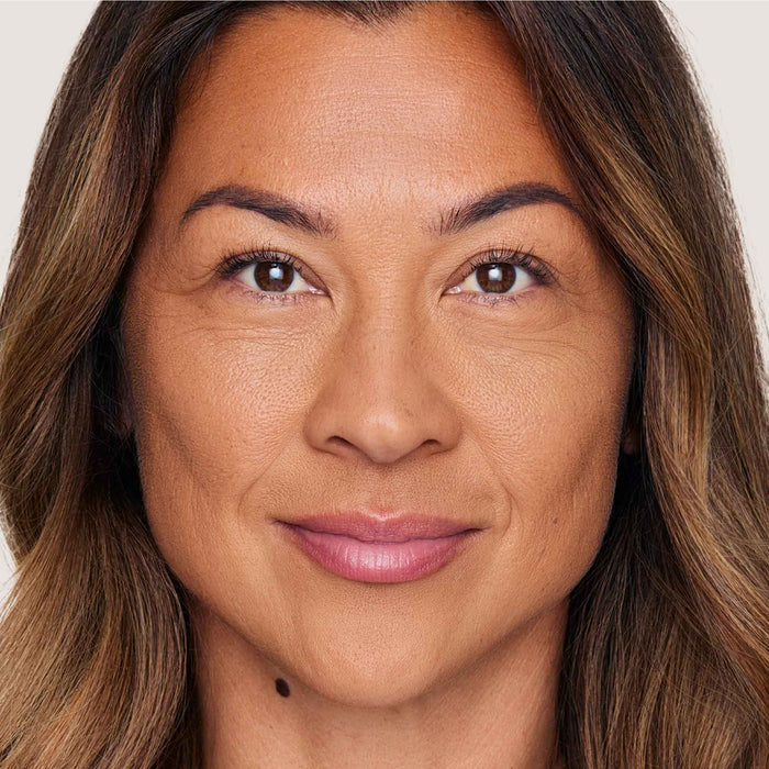 An image of a woman wearing FlexShade Foundation by No Makeup Makeup in Tan