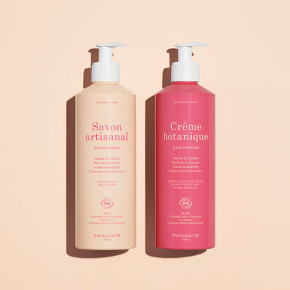 Two Manucurist pump bottles on beige: the light pink is Organic Orange Blossom Hand  Body Wash - Cosmos Organic, the dark pink is Crème botanique. Both for hand and body, scented with orange blossom.