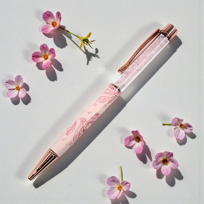 Pink pen with rose gold accents on a white background with pink flowers.