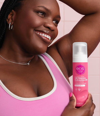 Woman holding a pink bottle of eos hair care product against a pink background
