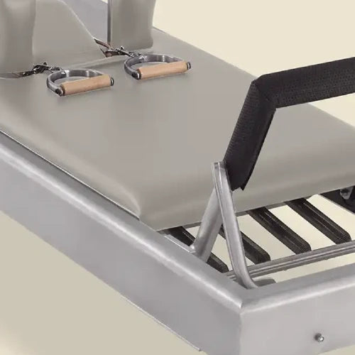 Dove-gray pre-stitched Pilates reformer upholstery fitted on an aluminum carriage with handles and strap.